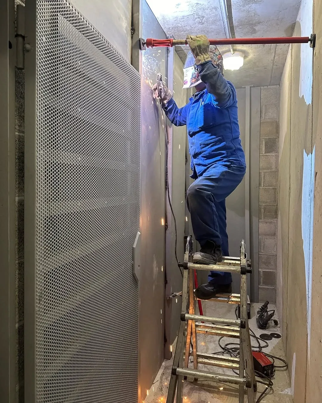 Operari de SEMPA serveis soldant un tancament de xapa perforada en un edifici